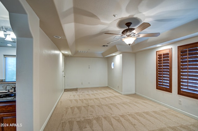 unfurnished room featuring light carpet, ceiling fan, sink, and a raised ceiling