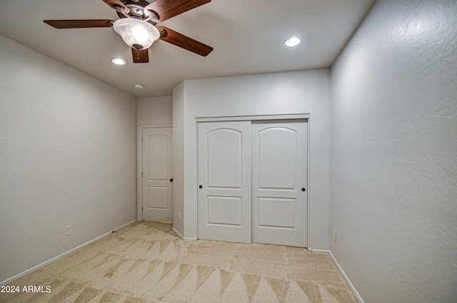 unfurnished bedroom featuring light colored carpet, ceiling fan, and a closet