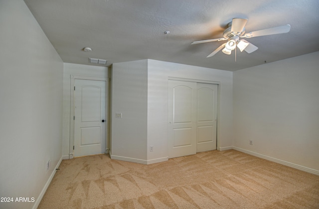 unfurnished bedroom with light colored carpet, ceiling fan, and a closet