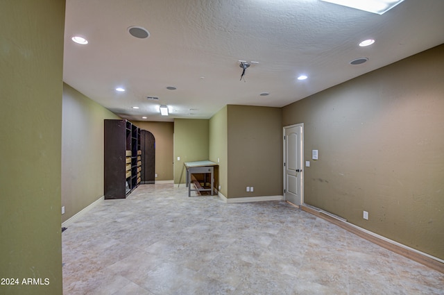 basement with a textured ceiling and light tile floors