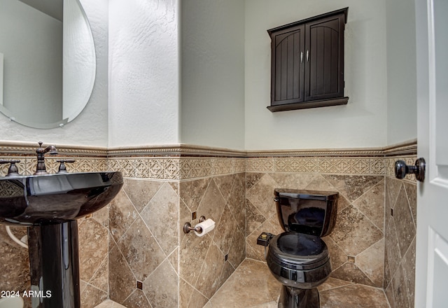 bathroom with toilet, tile walls, and sink