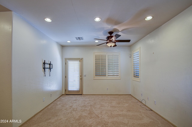 carpeted empty room with ceiling fan and a wealth of natural light