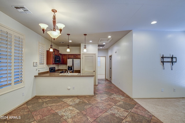 kitchen featuring dark colored carpet, decorative light fixtures, stove, stainless steel fridge, and a chandelier