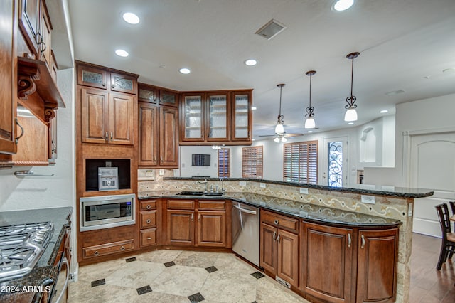 kitchen with decorative light fixtures, kitchen peninsula, appliances with stainless steel finishes, dark stone counters, and ceiling fan