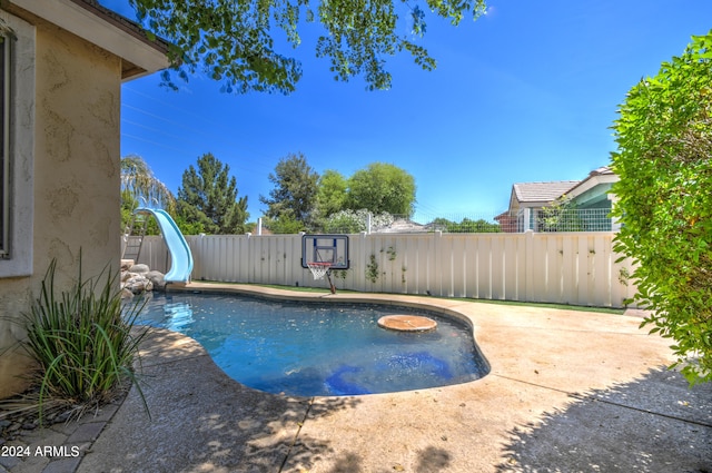 view of swimming pool with a water slide and a patio area