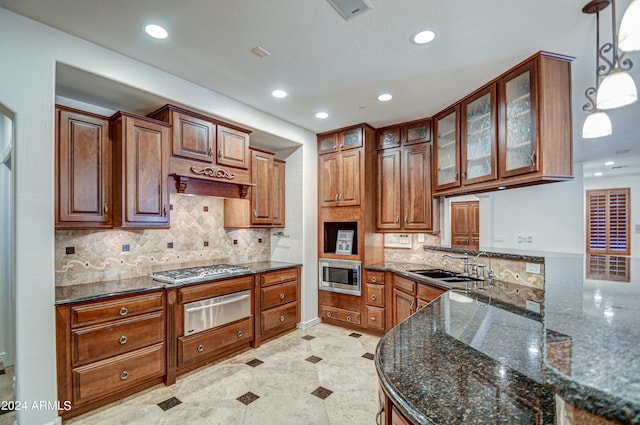 kitchen featuring appliances with stainless steel finishes, light tile floors, tasteful backsplash, hanging light fixtures, and dark stone countertops