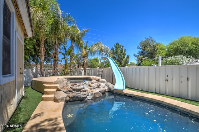 view of swimming pool featuring a hot tub and a water slide