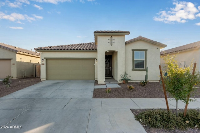mediterranean / spanish house featuring concrete driveway, stucco siding, an attached garage, and a tile roof