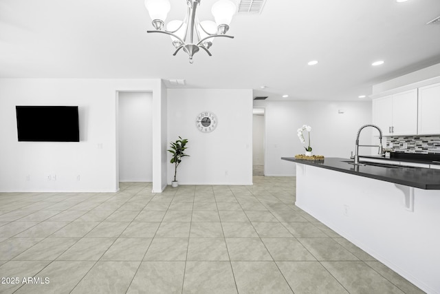 kitchen with a sink, tasteful backsplash, visible vents, recessed lighting, and dark countertops