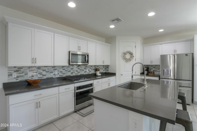 kitchen with white cabinets, appliances with stainless steel finishes, a kitchen island with sink, and sink