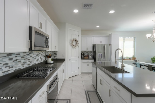 kitchen featuring stainless steel appliances, sink, light tile patterned floors, a center island with sink, and white cabinets