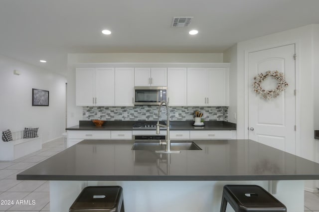 kitchen with white cabinets, tasteful backsplash, a kitchen island with sink, and sink