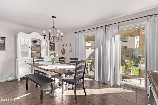 dining space with an inviting chandelier, plenty of natural light, and dark tile patterned floors