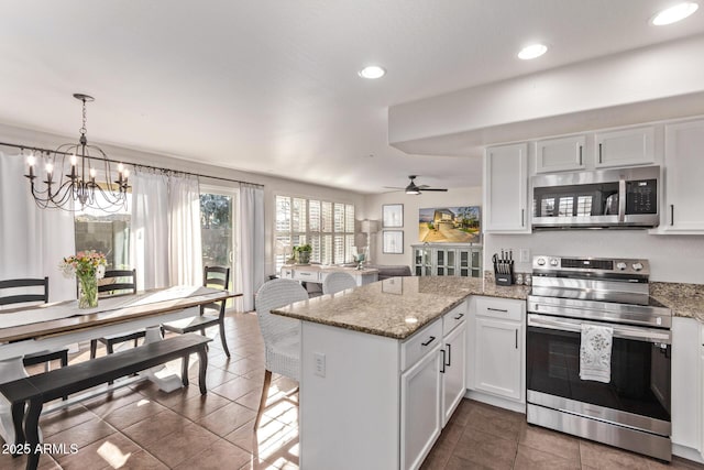 kitchen featuring stainless steel appliances, light stone countertops, kitchen peninsula, and white cabinets