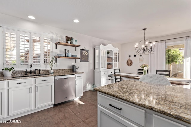 kitchen with sink, white cabinetry, an inviting chandelier, dishwasher, and dark stone counters