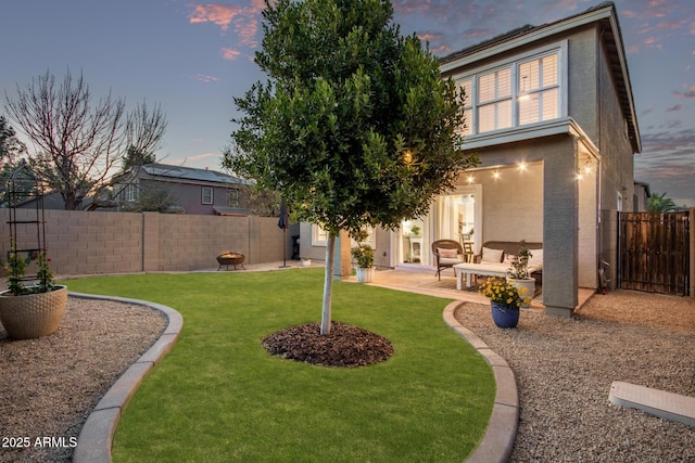 yard at dusk with an outdoor living space and a patio area