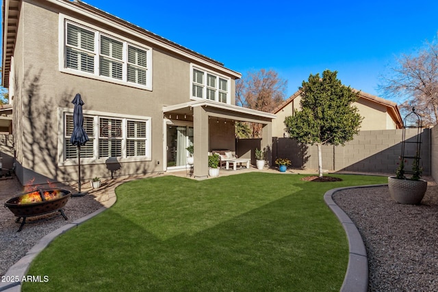 rear view of property featuring a lawn, a patio area, and a fire pit