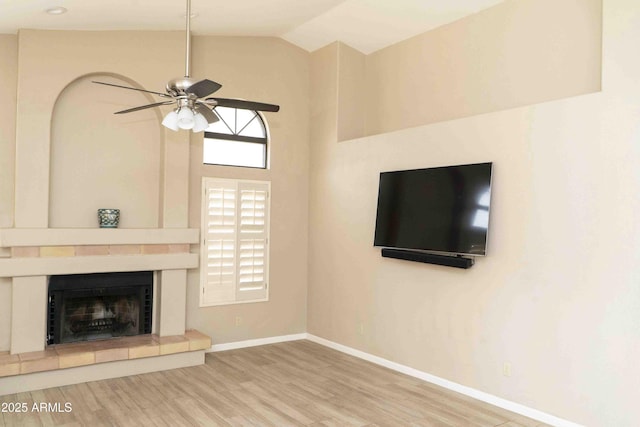 unfurnished living room featuring a fireplace, lofted ceiling, a ceiling fan, wood finished floors, and baseboards