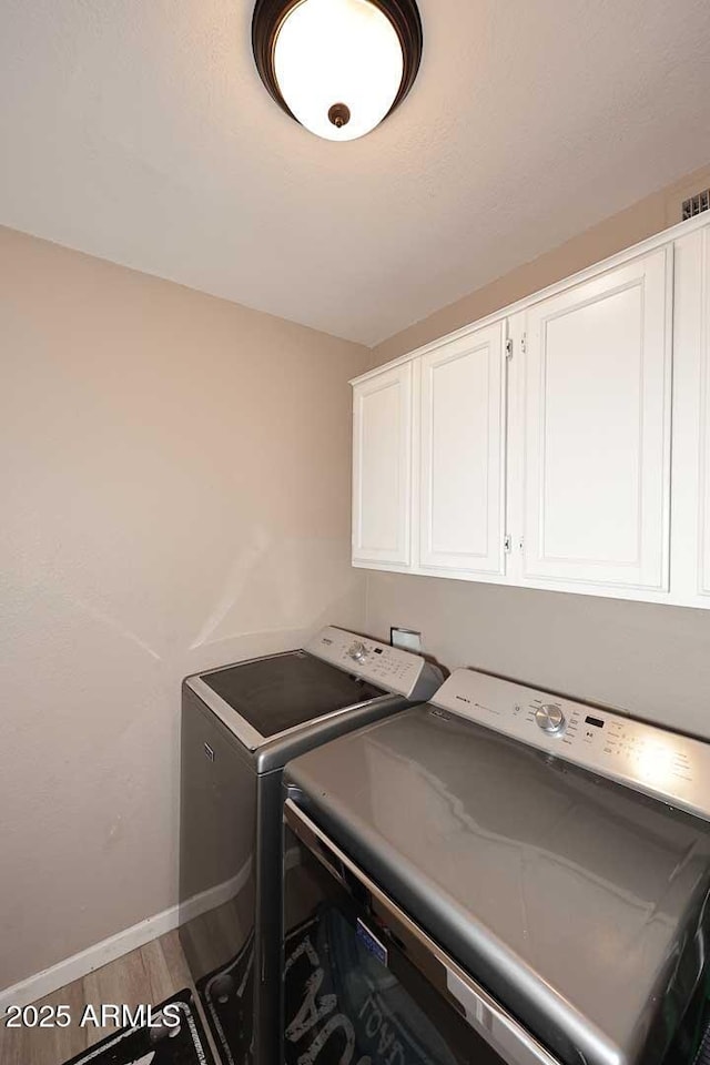 laundry area featuring baseboards, cabinet space, independent washer and dryer, and light wood finished floors