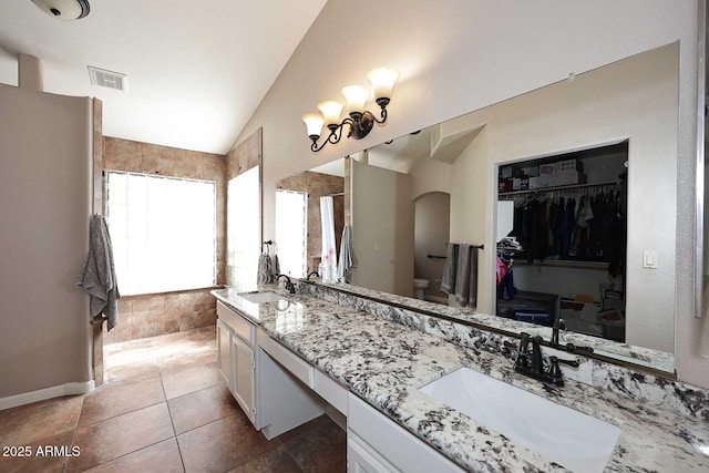 full bathroom with lofted ceiling, visible vents, a sink, and double vanity