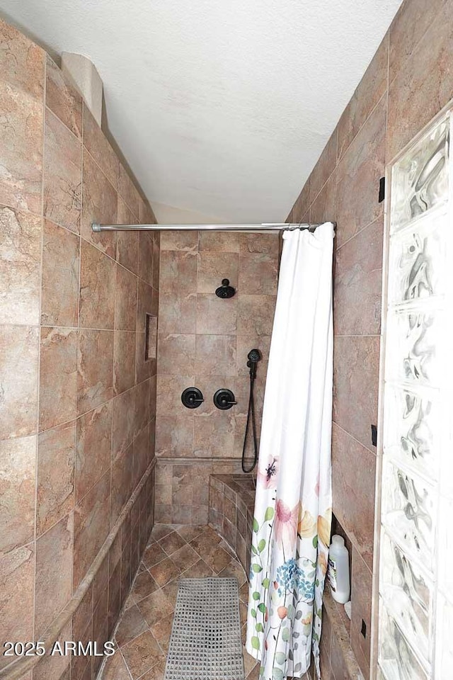 bathroom featuring a tile shower and a textured ceiling