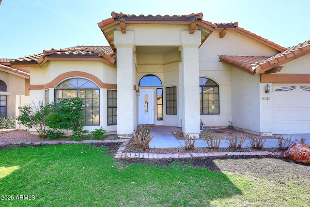 view of front of home with a garage, a tile roof, a front lawn, and stucco siding