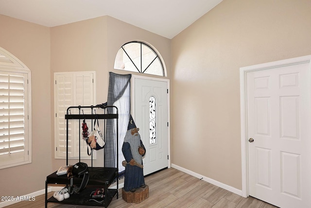 entrance foyer with light wood finished floors, baseboards, and vaulted ceiling