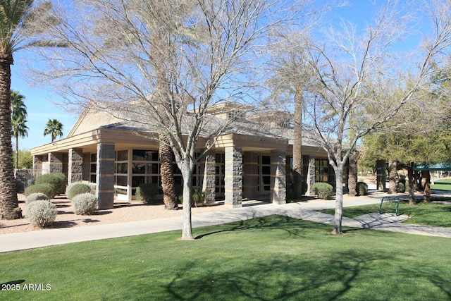 back of property featuring stone siding and a lawn