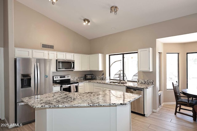 kitchen with visible vents, appliances with stainless steel finishes, light stone countertops, white cabinetry, and a sink