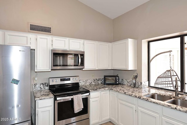 kitchen featuring stainless steel appliances, visible vents, light stone counters, and white cabinetry