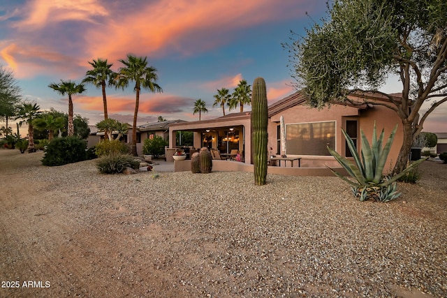 back of property at dusk with a patio and stucco siding