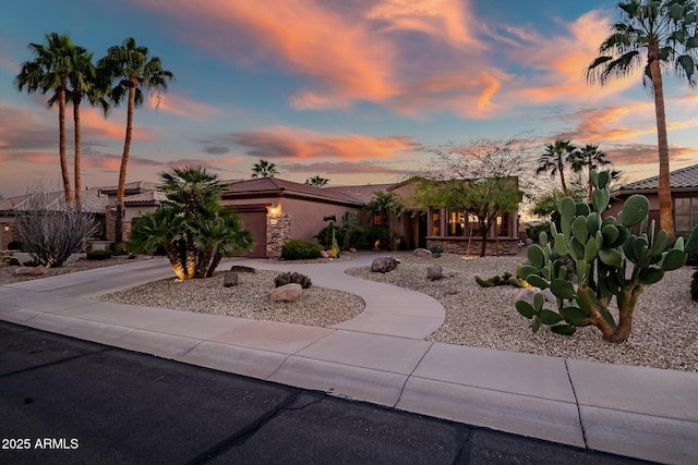 mid-century inspired home with stone siding, concrete driveway, an attached garage, and stucco siding