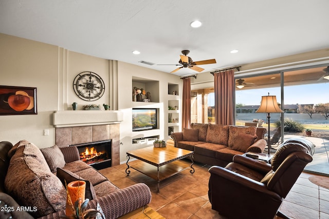 living area featuring built in shelves, a tile fireplace, recessed lighting, and light tile patterned floors