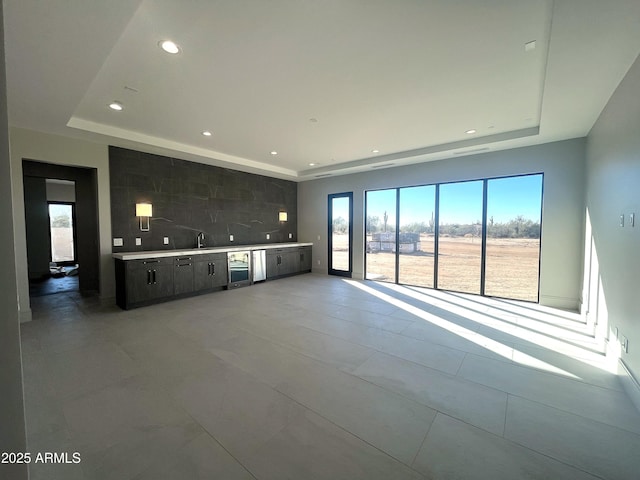 unfurnished living room featuring wine cooler and a tray ceiling