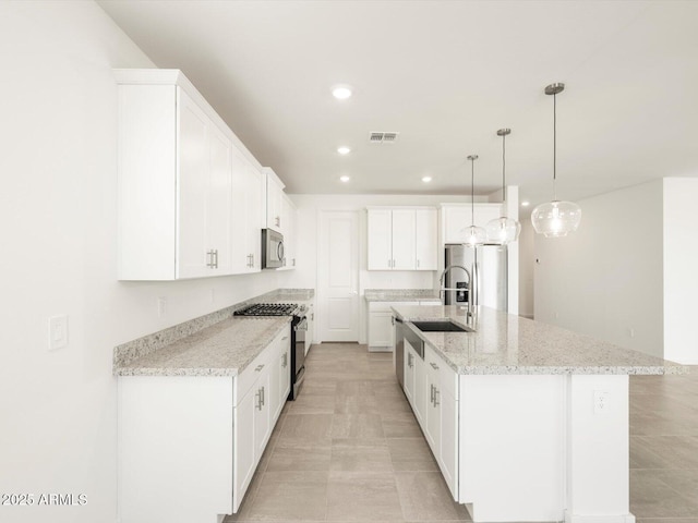 kitchen with white cabinetry, a center island with sink, stainless steel appliances, decorative light fixtures, and light stone countertops