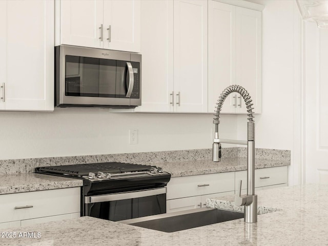 kitchen with white cabinets, light stone countertops, sink, and stainless steel appliances