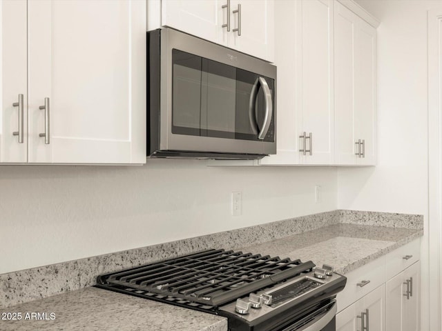 kitchen featuring white cabinets, appliances with stainless steel finishes, and light stone counters