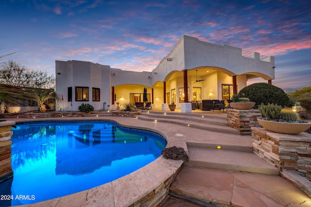 pool at dusk featuring a patio and ceiling fan