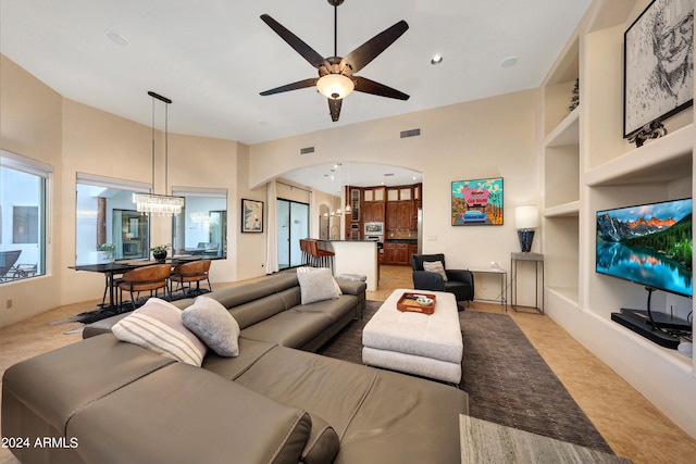 living room featuring ceiling fan with notable chandelier and built in features