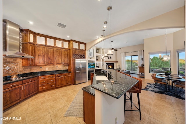 28217 N 139th St, Scottsdale, AZ 85262 - kitchen featuring stainless steel fridge with ice dispenser, wall chimney exhaust hood, open floor plan, light tile patterned floors, and a warm lit fireplace