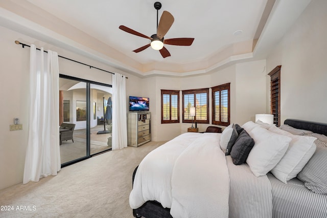 carpeted bedroom featuring ceiling fan, access to outside, and a tray ceiling