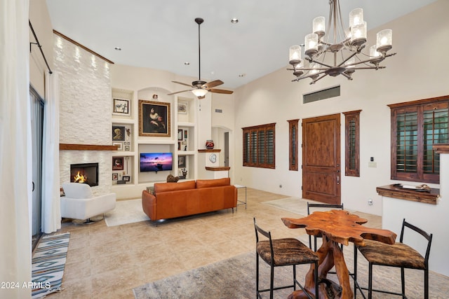 dining area with a high ceiling, a fireplace, ceiling fan with notable chandelier, and built in features