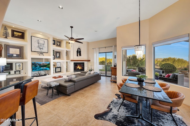 tiled living room featuring ceiling fan with notable chandelier and built in features