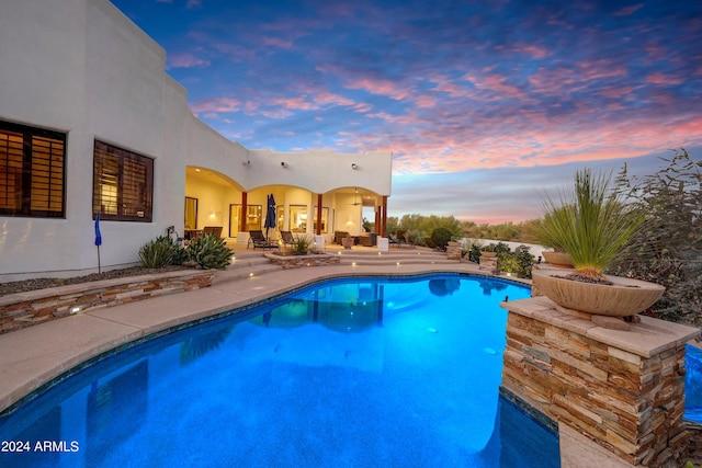 pool at dusk with a patio area