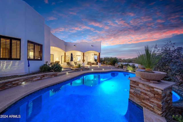 pool at dusk with a patio area