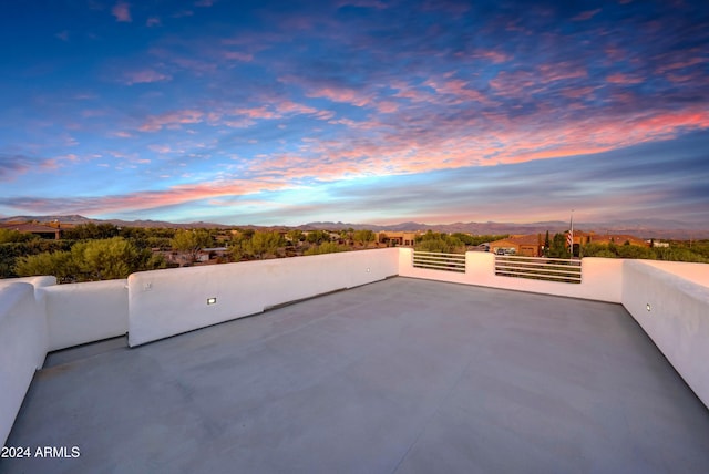 patio terrace at dusk featuring a mountain view and a balcony