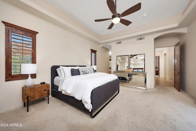 carpeted bedroom with a tray ceiling and ceiling fan