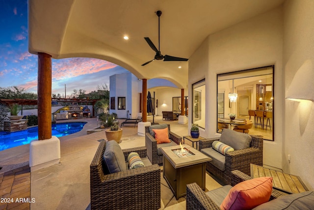 patio terrace at dusk with a swimming pool with hot tub, an outdoor living space with a fire pit, and ceiling fan