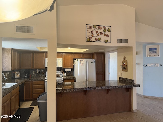 kitchen featuring white appliances, tile counters, visible vents, and a sink