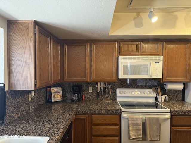 kitchen featuring tasteful backsplash, brown cabinets, white appliances, and dark countertops